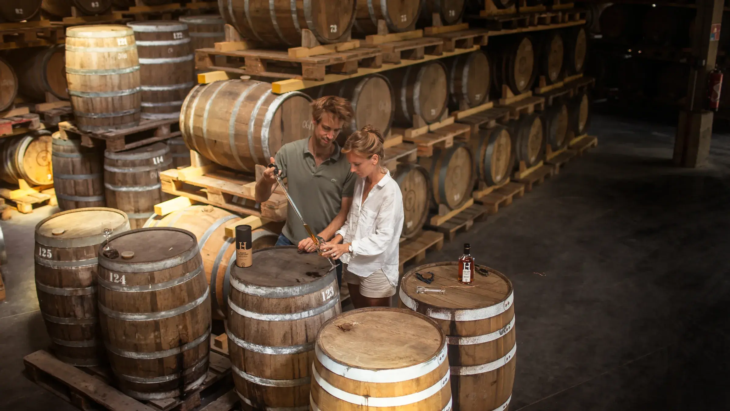 Étienne et Marie-Astrid d’Hautefeuille entre les fûts de chêne du chai de la distillerie