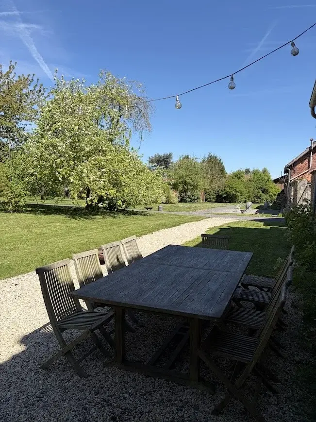 La terrasse du gîte avec sa grande table en bois donnant sur le verger