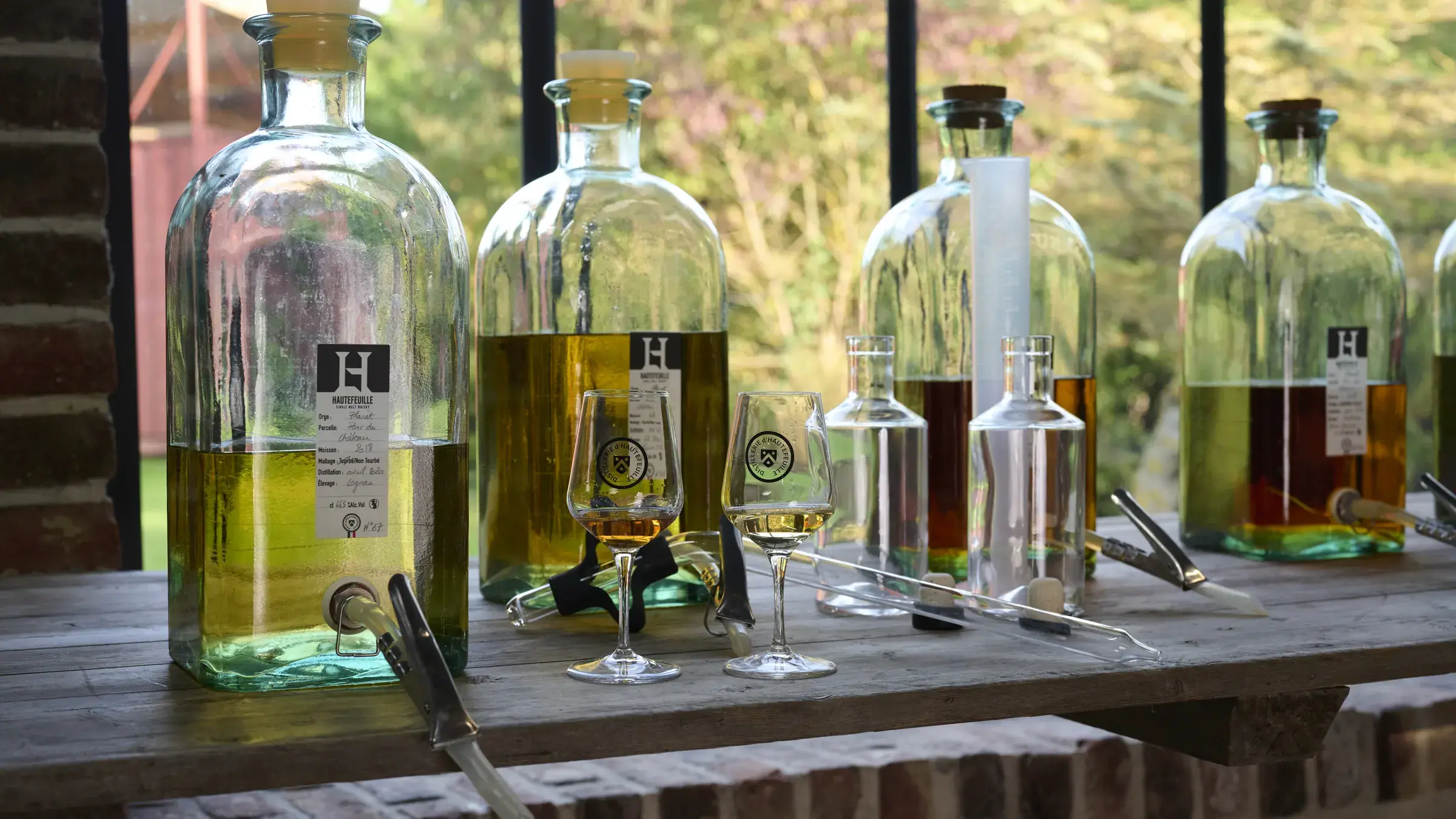Flacons d’échantillons de whisky alignés devant la verrière de l’atelier d’assemblage
