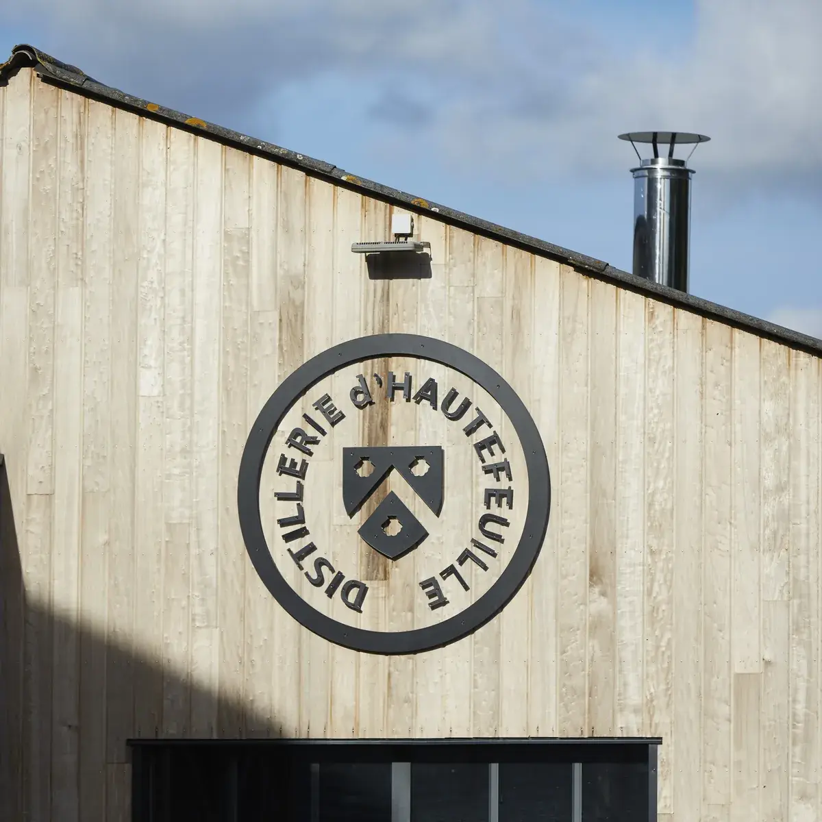 La façade en bois de la distillerie d’Hautefeuille, marquée du sceau du domaine