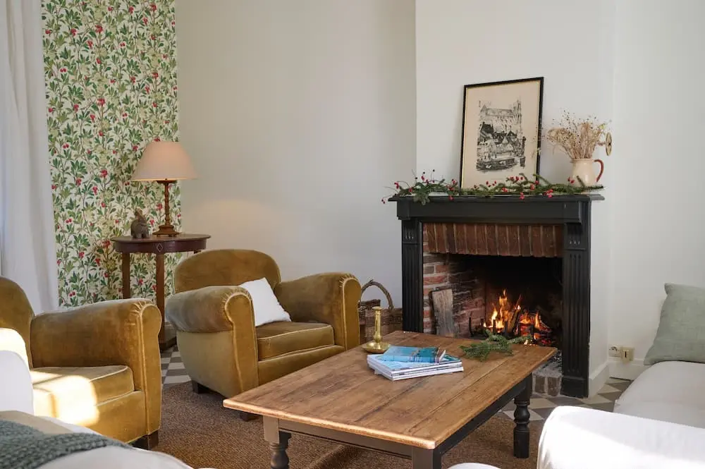 Le feu de cheminée du salon du gîte, ses fauteuils en velours et sa table basse en bois