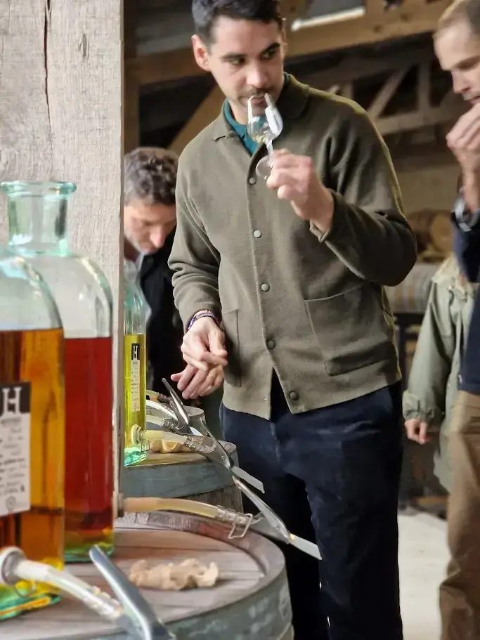 Un participant sent une éprouvette de whisky au-dessus d’une barrique servant de table d’assemblage