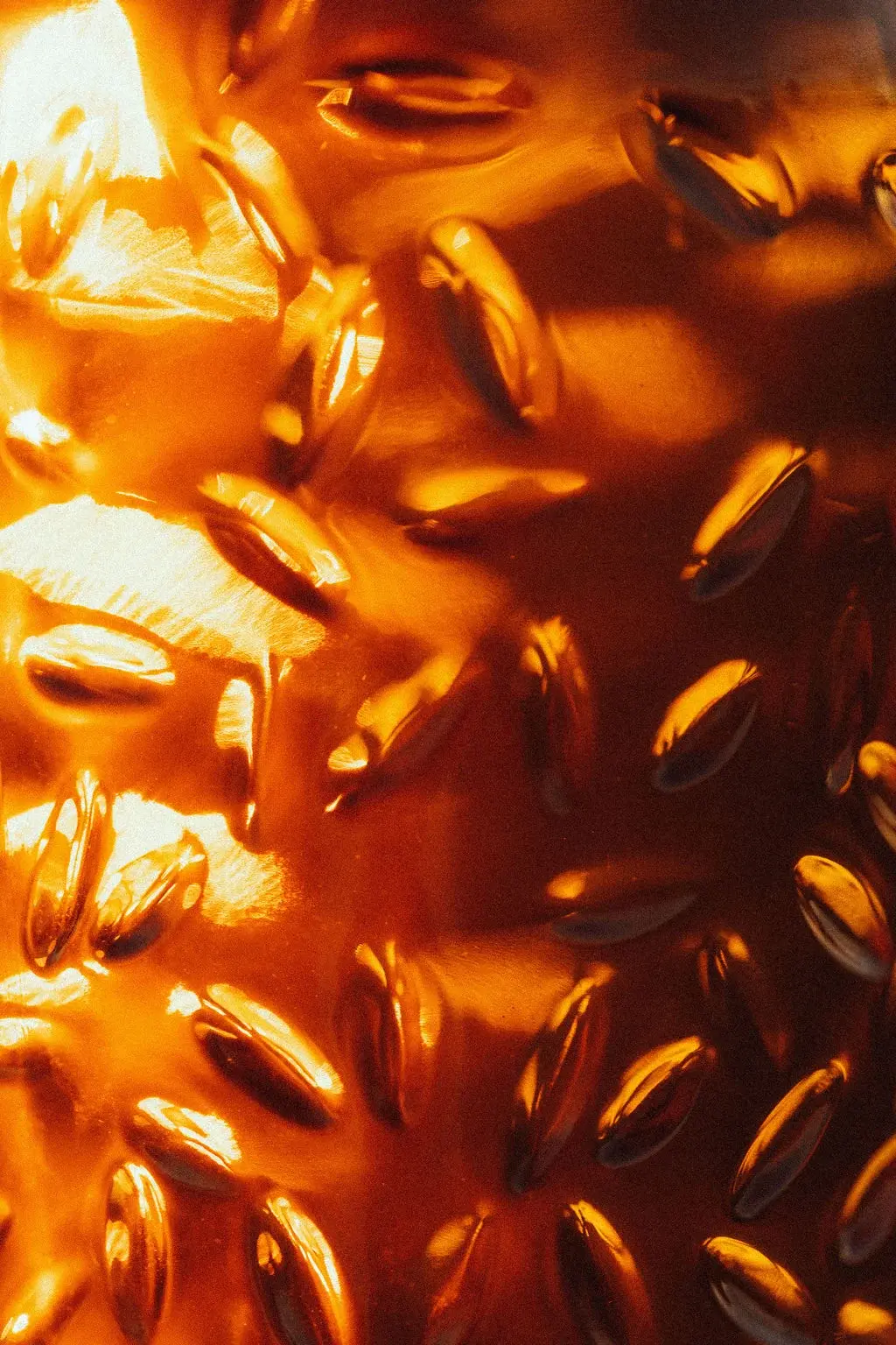 Le verre du flacon, gaufré de grains d’orge, en très gros plan dans la lumière du soir