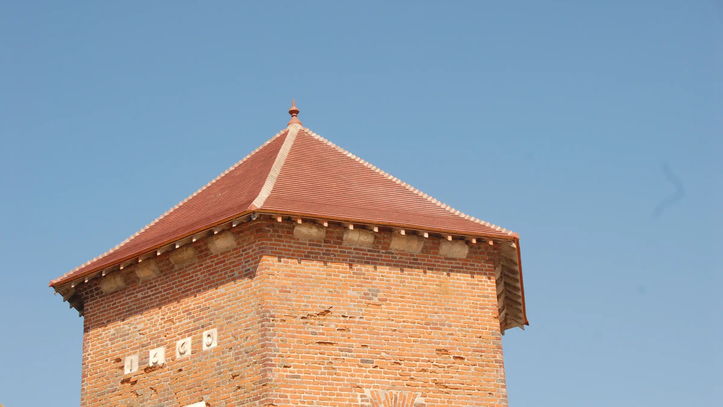 Pigeonnier en brique à toit d’ardoise sous un ciel bleu