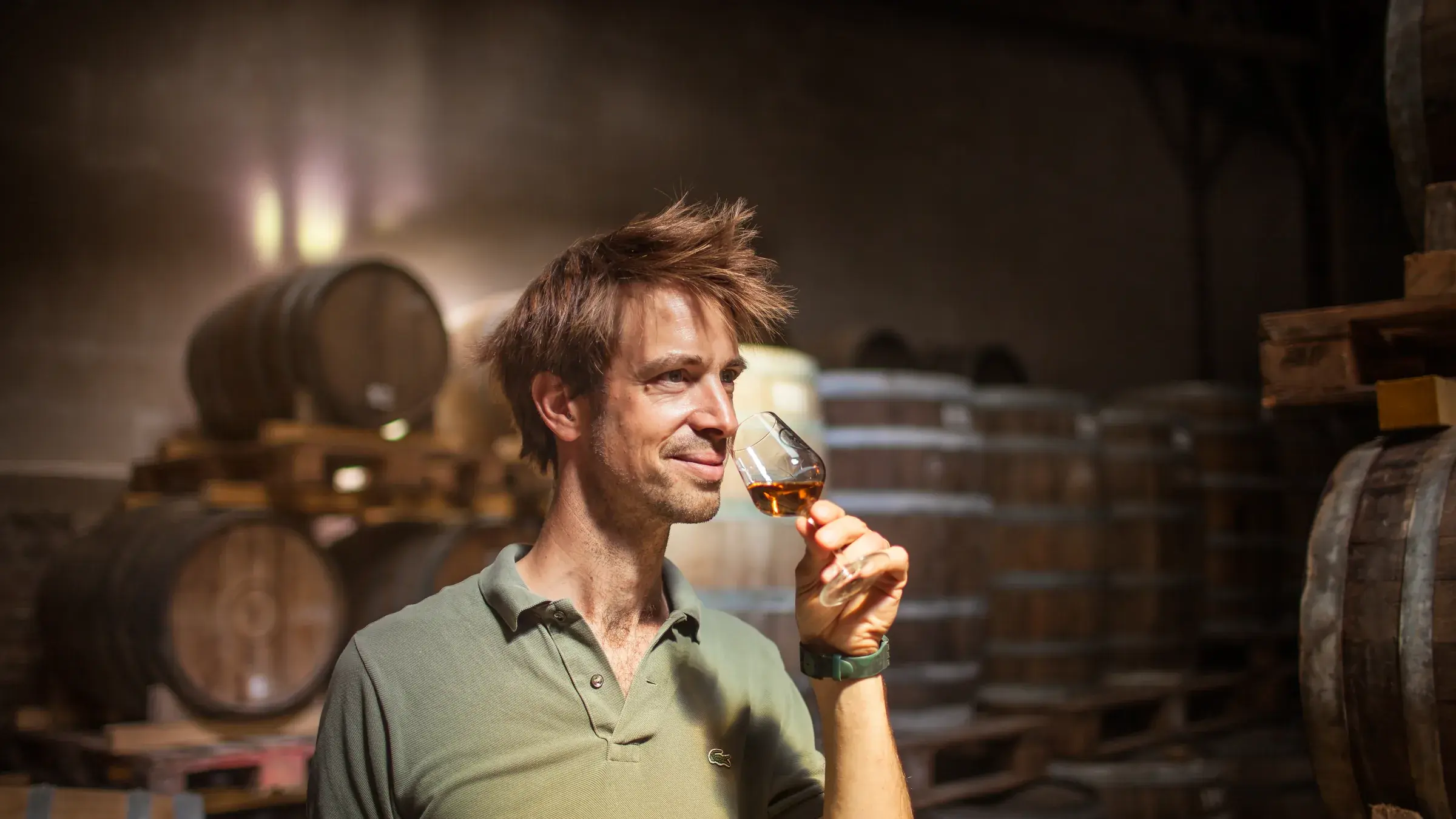 Étienne d’Hautefeuille sent un verre de whisky dans la pénombre du chai