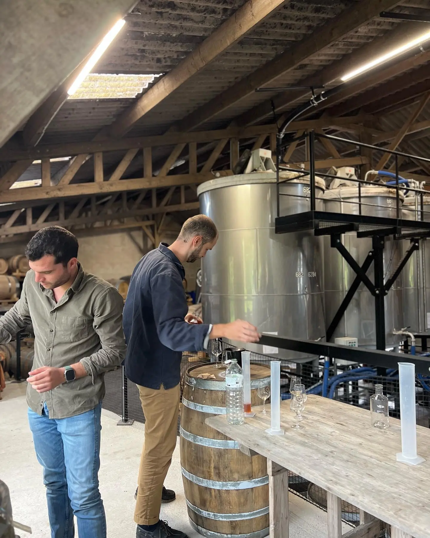 Atelier autour des cuves de la distillerie, éprouvettes et verres de dégustation sur la table