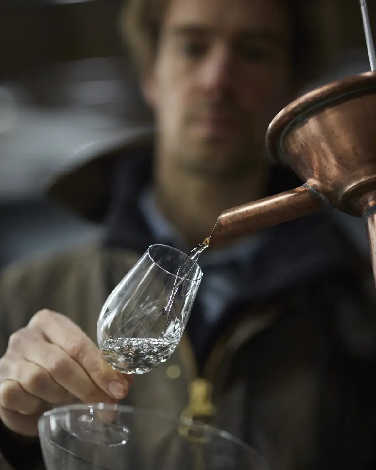 Étienne recueille le distillat qui coule de l’alambic dans un verre